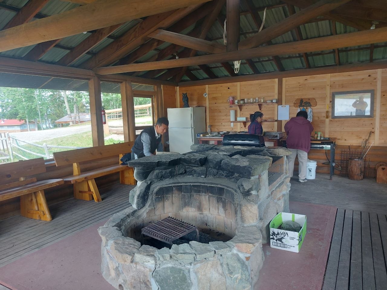 Community members grilling at a screened-in lakeside BBQ house at Lifechanyuan's Canada resort home, ...