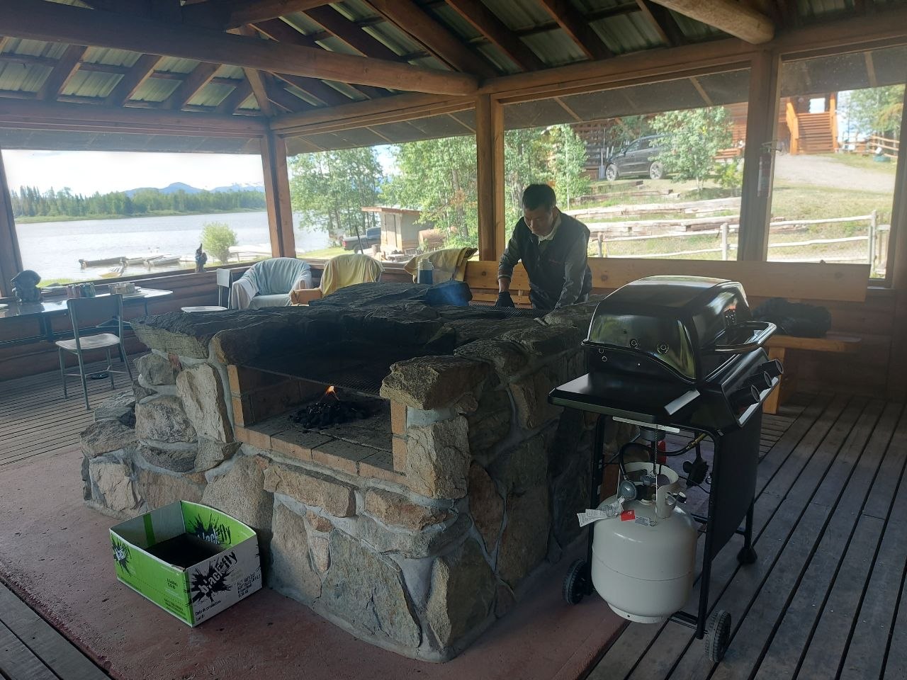 Community members grilling at a screened-in lakeside BBQ house at Lifechanyuan's Canada resort home, ...