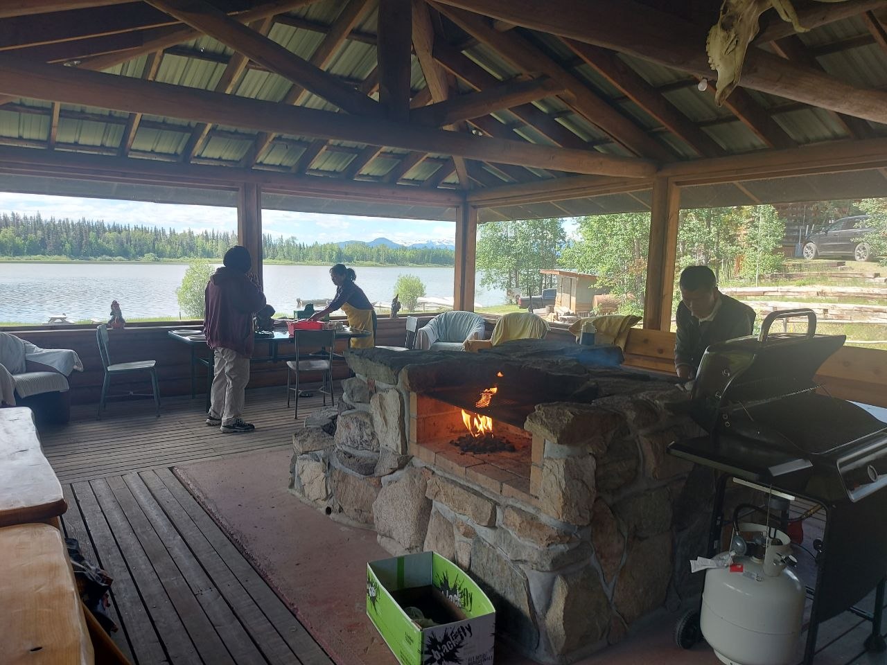 Community members grilling at a screened-in lakeside BBQ house at Lifechanyuan's Canada resort home, ...