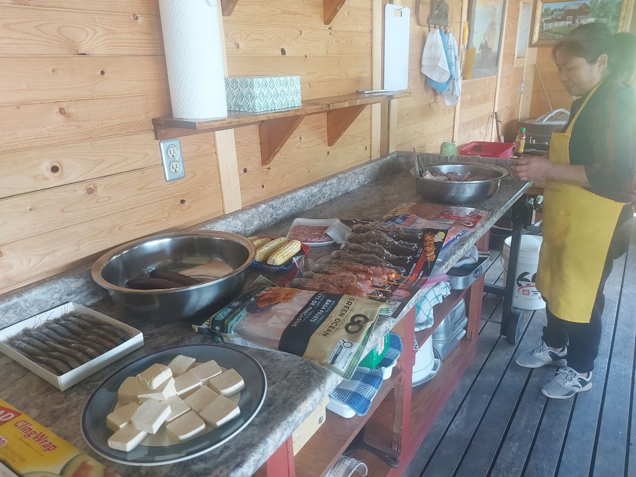 Community members grilling at a screened-in lakeside BBQ house at Lifechanyuan's Canada resort home, ...